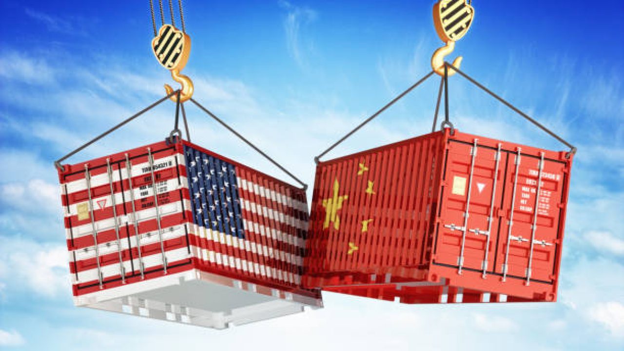 Freight transportation concept, cargo containers with USA and China flags hoisted by crane hooks on blue cloudy sky background